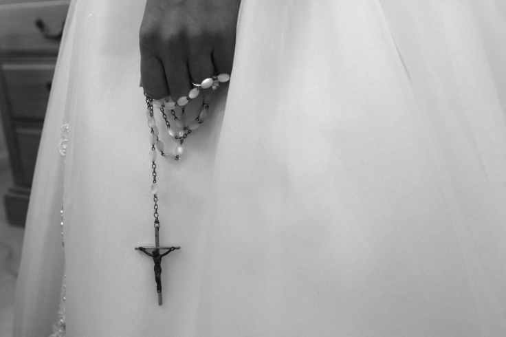 grayscale photo of person holding rosary